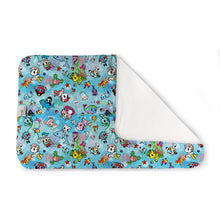 Load image into Gallery viewer, Kanga Care Changing Pad and Sheet Saver in the print called tokiSea tokidoki in a light blue background with Unicornos and an all-over cartoon character print, shown with one corner folded over to reveal a white reverse side, on a plain white background.