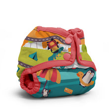 Load image into Gallery viewer, Rumparooz Newborn Cloth Diaper Cover by Kanga Care in the print called Trej with a playful cartoon penguins and road-pattern print, featuring coral pink adjustable straps and snap closures, shown on a clean white background.