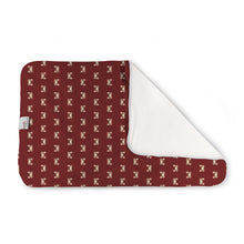 Load image into Gallery viewer, Kanga Care Changing Pad and Sheet Saver in the print called Sebastian with a repeating cream monogram pattern, shown folded with a white plush backing visible on one side. A small fabric tag is visible on the left edge.