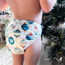 Load image into Gallery viewer, Baby standing at a Christmas tree wearing a Rumparooz G3 One Size Pocket Cloth Diaper in Christmas print called Glaskugeln with blue and red ornament pattern on a white background