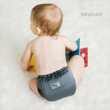Load image into Gallery viewer, Baby sitting on the floor reading a book and wearing a Rumparooz One Size Cloth Diaper in the color Castle