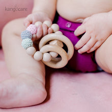 Load image into Gallery viewer, Baby sitting in a Boysenberry Ecoposh OBV, holding a Blush teething ring