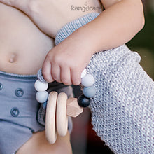 Load image into Gallery viewer, Baby in a Glacier Ecoposh OBV holding a Pebble Teething Ring