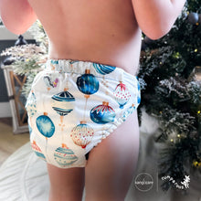 Load image into Gallery viewer, Baby standing at a Christmas tree wearing a Rumparooz G3 One Size Pocket Cloth Diaper in Christmas print called Glaskugeln with blue and red ornament pattern on a white background
