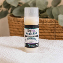 Load image into Gallery viewer, GroVia Magic Stick balm on a textured surface with a blurred plant background
