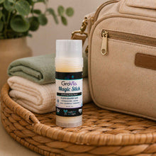 Load image into Gallery viewer, GroVia Magic Stick on a woven surface with a beige bag and folded cloths in the background
