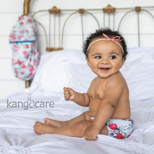 Load image into Gallery viewer, Baby sitting on a bed wearing a Lily Rumparooz One Size Cloth Diaper and a Kanga Care Wet Bag hanging in the backgound
