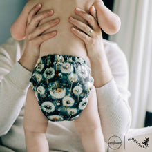 Load image into Gallery viewer, Man holding a baby wearing a dandelion cloth diaper, with 'Rumparooz' by Kanga Care branding visible.
