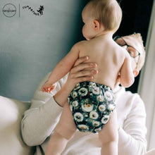 Load image into Gallery viewer, Man holding a baby wearing a dandelion cloth diaper, with 'Rumparooz' by Kanga Care branding visible.
