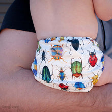 Load image into Gallery viewer, Bugs Rumparooz OBV One Size Cloth Diaper on a baby being held by dad

