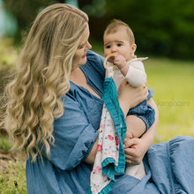 Load image into Gallery viewer, Mom holding baby who is chewing on a Lily teething blanket
