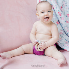 Load image into Gallery viewer, Baby sitting in a Boysenberry Ecoposh OBV, holding a Blush teething ring
